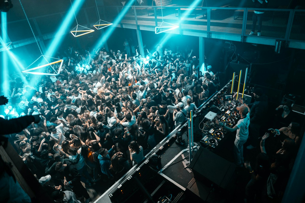 DJ booth overlooking a packed indoor dancefloor under blue lights