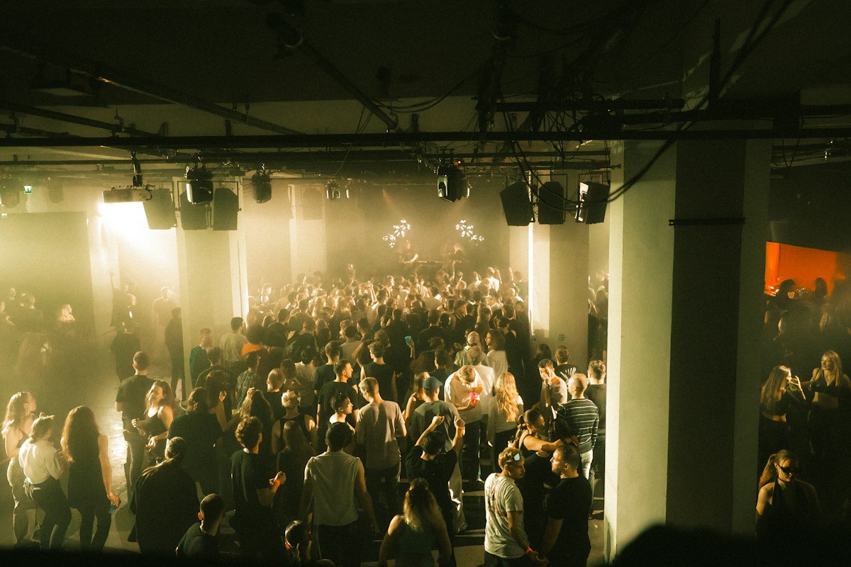A smoky indoor club filled with dancers under warm lighting